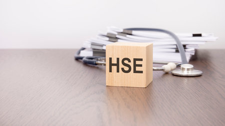 wooden cube with black letters HSE, stethoscope, book, notepad on white wooden table. medical and education concept.の写真素材