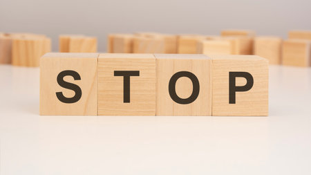 wooden cubes standing on a white table against a gray wall, inscribed with STOPの写真素材