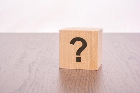 three wooden blocks with question marks over a gray background with copy spaceの写真素材