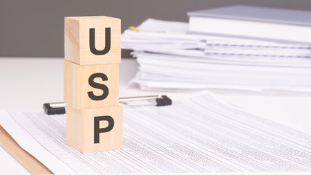USP - Unique Selling Proposition on wooden blocks against a backdrop of business papers conveys a finance concept emphasizing individuality and market distinctionの写真素材