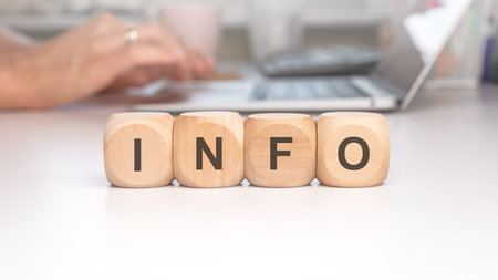 INFO wooden blocks symbolizing information on a desk with a laptop, representing business and digital data.の写真素材