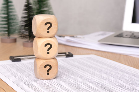 A stacked arrangement of wooden blocks with question marks symbolizes curiosity and provokes thought and imaginationの写真素材