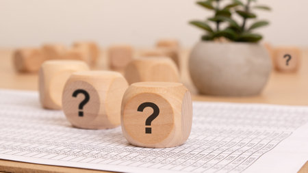 Wooden blocks with symbols questions on paper and a plant for effective business conceptsの写真素材