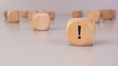 small wooden cube with exclamation point in black on the side over a brown backgroundの写真素材
