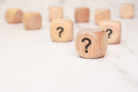 scattered wooden cubes with question marks representing uncertainty, business risk, strategic decision-making, problem-solving, and critical thinking in personal and corporate environmentsの写真素材