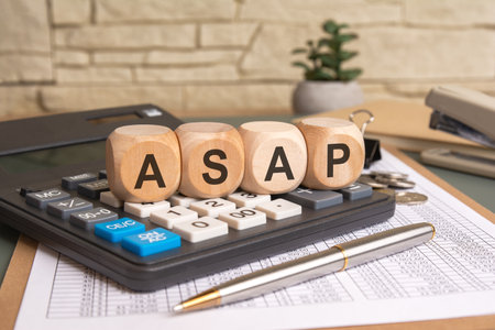 ASAP word on wooden cubes placed on a calculator with financial papersの写真素材