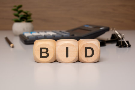 cubes displaying the letters BID placed neatly on a light-colored office desk. Ideal for themes like customer support, communicationの写真素材