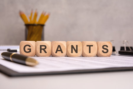 Word GRANTS on wooden blocks with office supplies in background.の写真素材