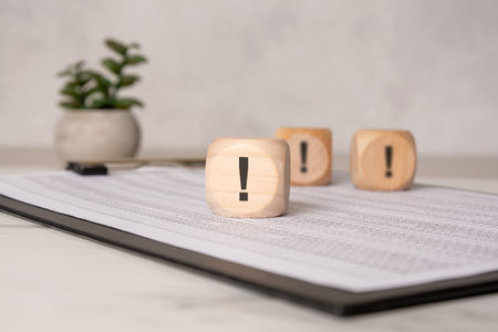 Wooden cubes with exclamation marks on financial documents, concept of attention or warningの写真素材
