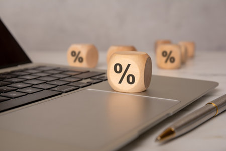 Wooden dice with percent symbols placed on a laptop, symbolizing interest rates, finance, or taxes.の写真素材