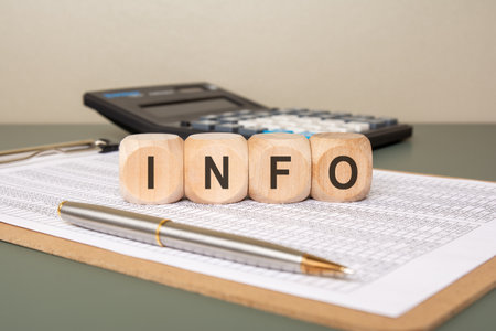Four rounded wooden cubes with black capital letters spelling INFO. A blurred office background with a potted plant adds context.の写真素材