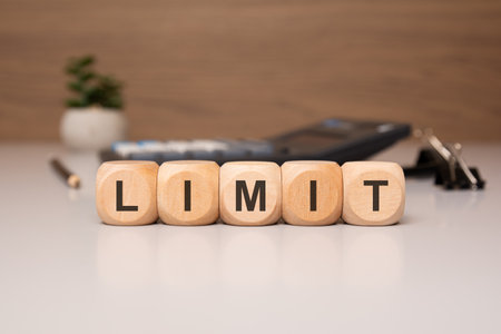 Conceptual image with wooden cubes spelling LIMIT on a desk, symbolizing financial or legal...