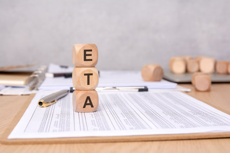 stacked wooden cubes with ETA acronym on office desk with financial reports and pen, close-up viewの写真素材