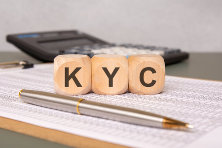 Wooden blocks displaying KYC (Know Your Customer) on a financial spreadsheet with a pen and calculator. Symbolic image for banking, compliance, identity verification, and finance.の写真素材