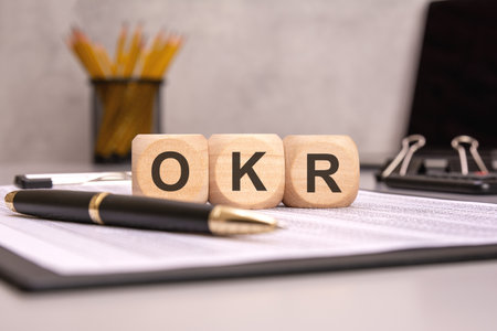 wooden cubes spelling OKR on a desk with pen and documentsの写真素材