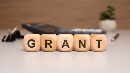 Close-up of wooden cubes with the word GRANT, representing financial support, funding, scholarship,...