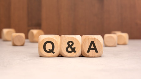 Wooden cubes with the letters Q and A on a wooden surface with a brown background. Concept of...