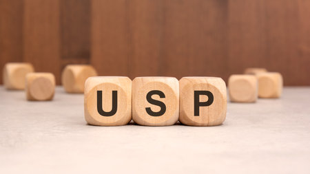 Close-up of wooden blocks with the inscription USP, representing Unique Selling Proposition. Business, marketing and branding strategy concept on reflective table backgroundの写真素材
