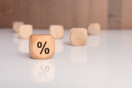 close-up of a wooden cube with a percent symbol on a white glossy surface. concept of finance, interest rates, profit, discount, or business growth. minimalist financial background.の写真素材