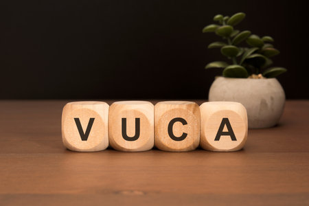 Wooden cubes with VUCA abbreviation (Volatility, Uncertainty, Complexity, Ambiguity) symbolizing modern business environment, strategy, and leadership in unstable timesの写真素材