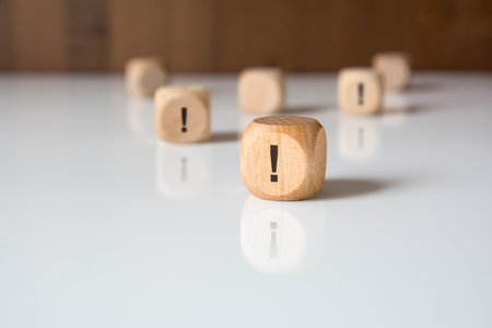 wooden cubes with exclamation mark symbols on white reflective surfaceの写真素材