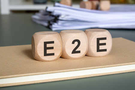 Wooden cubes with E2E abbreviation on a closed notebook. Concept of end-to-end process, integration, efficiency, workflow, and digital transformation in business management.の写真素材