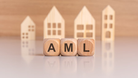 wooden cubes spelling AML in front of model houses, symbolizing anti-money launderingの写真素材