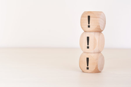 Business concept of importance, risk management, and priority. A vertical stack of three wooden blocks with exclamation marks on a neutral background with copy space. Symbolizes warnings, important announcements, alerts, and calls to action.の写真素材