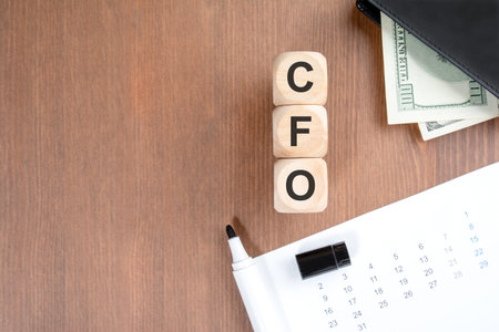 Vertical stack of wooden blocks spelling CFO (Chief Financial Officer) on a dark wooden background....