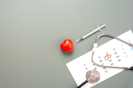 Horizontal high-angle view of a medical stethoscope, heart model, and syringe on a calendar with a...