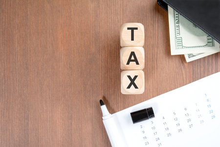 TAX word on wooden blocks with wallet, dollars and calendar. Tax return and financial planning...