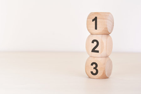 Minimalist top view of wooden toy blocks with numbers 1, 2, 3 stacked in a column on a bright...