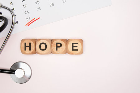 Top view flat lay of wooden toy blocks spelling the word HOPE on a bright neutral background....