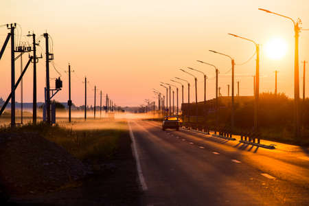 A car at sunset is driving along the roadのeditorial素材