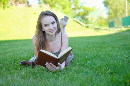 Beautiful young woman reading book at parkの写真素材