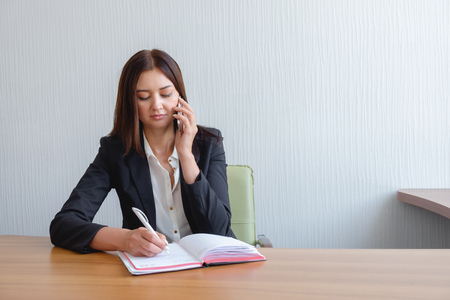 busy secretary is answering call and writing memo at the same timeの写真素材