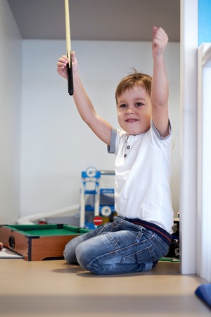 Little smiling boy is playing on a floor at home in billiardsの写真素材