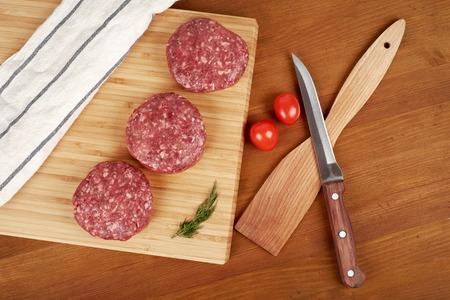 Raw cutlet of minced meat on a wooden cutting board.の写真素材