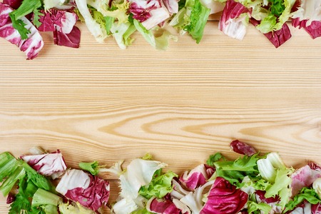 Frame of fresh green salad on wooden background. Healthy natural food . mockup for recipe or menu.の写真素材