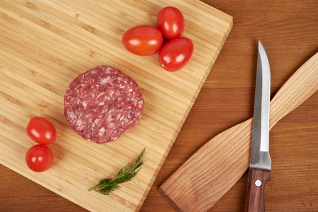 Raw cutlet of minced meat on a wooden cutting board.の写真素材