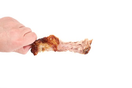 hand holding a nibbled chicken leg , isolated on white backgroundの写真素材