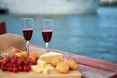 Two glasses of red wine, served outdoor with fruits and beautiful blue ocean view.の写真素材