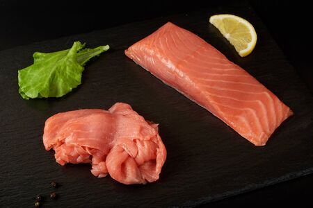 Sliced red fish fillet on the black shale board.の写真素材