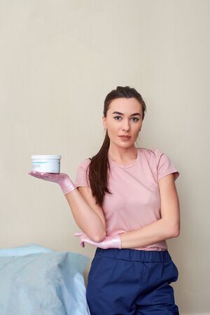 Beauty cosmetologist holding the bottle with lotion and presents product. Beautician presents and shows various cosmetics products.の写真素材