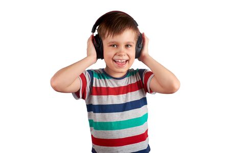 Child listens to his favorite music on headphones and dances to it , isolated on white background. Leisure, music and entertainment concept.の写真素材