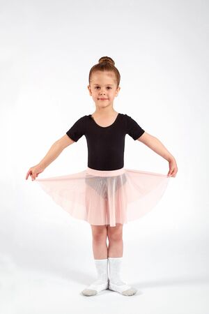 Little girl dressed in dance uniform is dancing over a white background in the studio.の写真素材