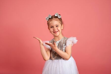 Portrait of a cute little girl in a beautiful dress that shows somewhere with her handsの写真素材