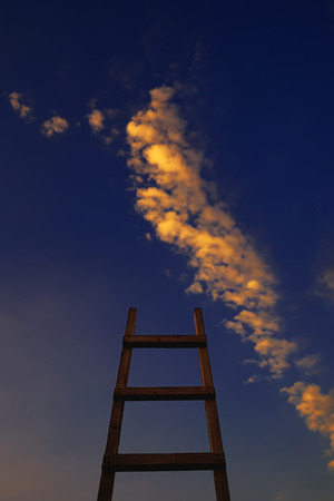 Conceptual shot of wooden ladder, directed to the blue sky with cloudsの写真素材
