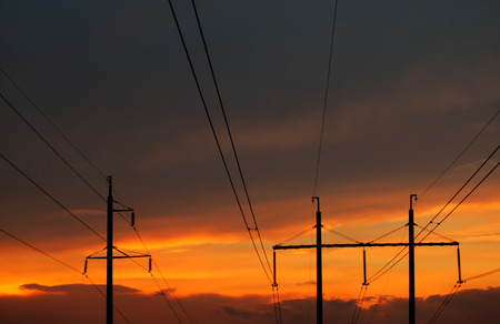 High voltage power line at sunset on a background of cloudy orange skyの写真素材