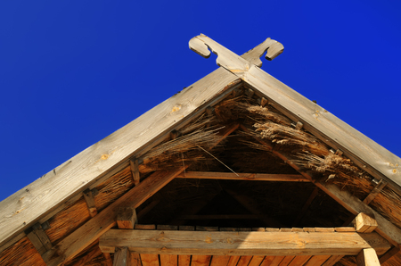 A wooden roof with an attic, covered with reeds - an element of Ukrainian national houseの写真素材